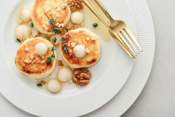 cottage cheese pancakes, syrniki, curd fritters served with pear balls, walnut and honey
