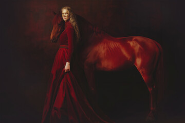 Young Beauty Woman in Red Dress and Bay Horse on a dark background. Year of the Horse concept