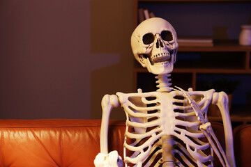 Human skeleton model sitting on couch in living room at night
