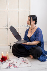 Sadhu board. Yoga tool. Woman sitting in lotus position hand holding sharp nails for practice candles meditation foot massage spiritual growth.