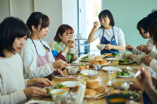 料理教室の後作った料理を囲んんで食事を楽しむ人々