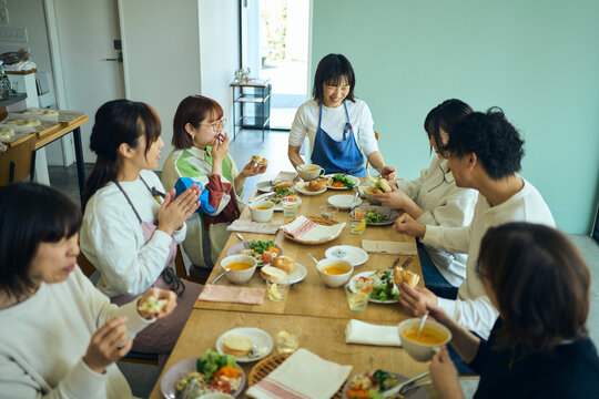 料理教室の後作った料理を囲んで食事を楽しむ人々