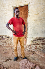village happy african man portrait, outdoors in the nature ,stone wall with door behind