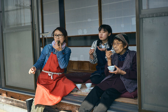 日本の縁側でおやつを食べながら休憩する
三世代の女性達