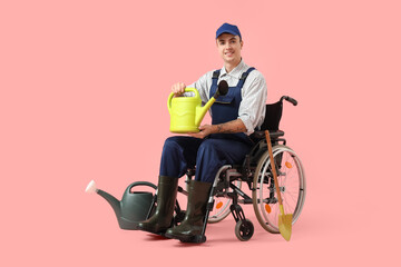 Fototapeta premium Male gardener in wheelchair with watering can on pink background. Equality concept
