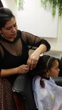 Hairdresser applying hair extensions to a young girl