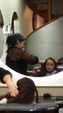 Hairdresser styling a young girl's long curly hair in a beauty salon