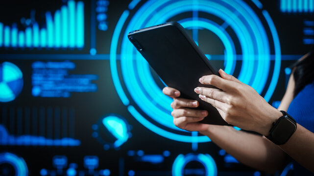 Woman holding tablet computer with futuristic blue data dashboard background, digital analytics, smart technology, data visualization, business intelligence, advanced user interface design. - Powered by Adobe
