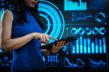 Woman holding tablet computer with futuristic blue data dashboard background, digital analytics, smart technology, data visualization, business intelligence, advanced user interface design.