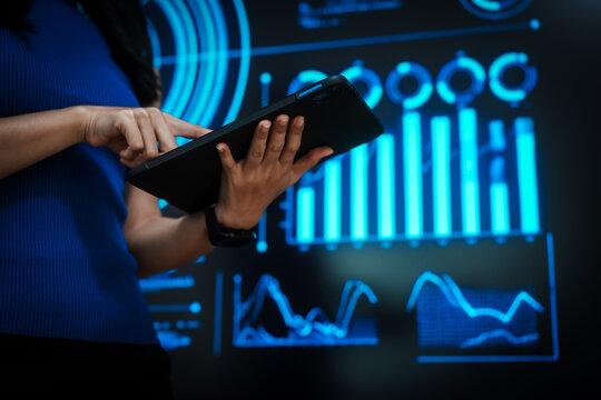 Woman holding tablet computer with futuristic blue data dashboard background, digital analytics, smart technology, data visualization, business intelligence, advanced user interface design. - Powered by Adobe