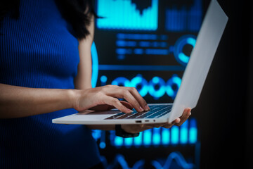 Professional woman working on laptop with futuristic data visualization background, representing digital analytics, business intelligence, productivity, advanced computing in high tech environment.