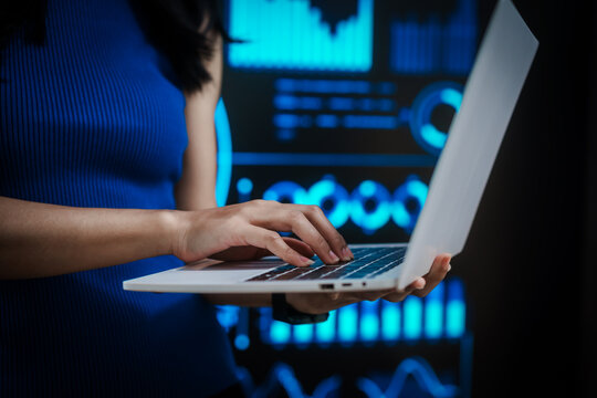 Professional woman working on laptop with futuristic data visualization background, representing digital analytics, business intelligence, productivity, advanced computing in high tech environment. - Powered by Adobe