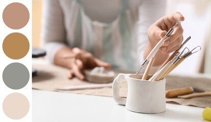 Female sculptor with clay figurine taking tools from holder in workshop, closeup. Different color...