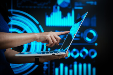 Professional woman working on laptop with futuristic data visualization background, representing digital analytics, business intelligence, productivity, advanced computing in high tech environment.