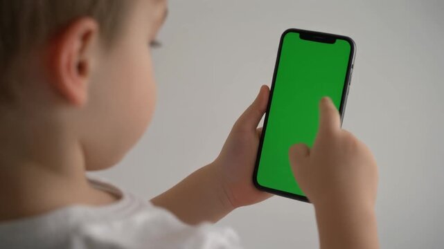 Child using smartphone with green screen, app concept, copy space