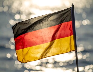 Close-up of flag waving in wind, water background, sunlight sparkling