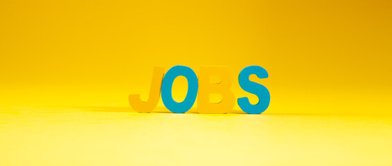 Jobs word made of wooden letters on yellow background. Job concept