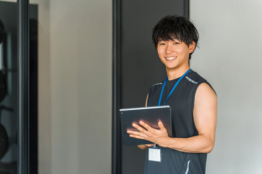 Male gym trainer, personal trainer, and instructor with tablet - Powered by Adobe