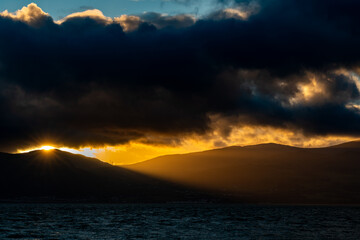 Sunrise over the Carneddau Mountains beneath dark, dramatic cloud cover