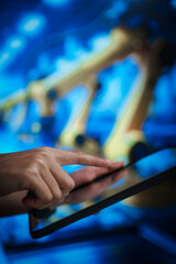 Woman using tablet computer in automated factory with robotic arms, representing smart industry, digital manufacturing, industrial technology, process control, innovation, modern production systems.