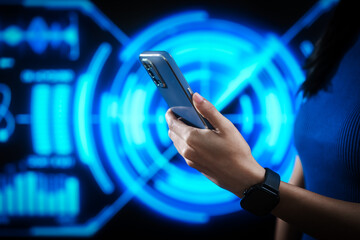 Woman using smartphone with smartwatch in futuristic blue digital interface background, representing smart technology, connectivity, innovation, data interaction, digital transformation.