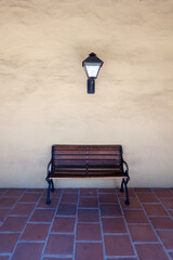 Wooden Bench and Wall Lantern Against Stucco Wall in Spanish Mission Architecture.
