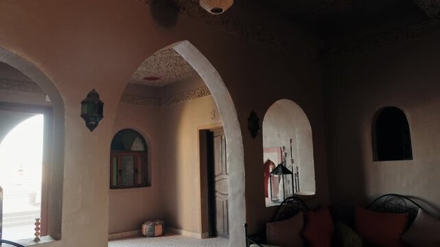 Traditional Moroccan interior design with arches, tiled floors, and vibrant colors. Sunlight streams through creating a warm ambiance. This video captures the essence of Moroccan architecture