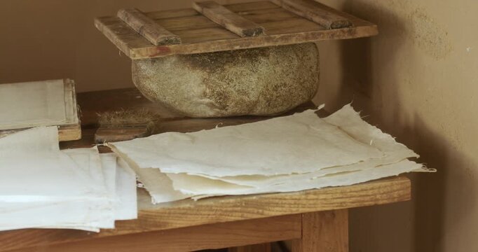 Handmade paper sheets drying beside traditional papermaking tools