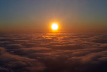 Landscape with sunset above the cloud layer. Aerial view of a sunset over the sea of ​​clouds