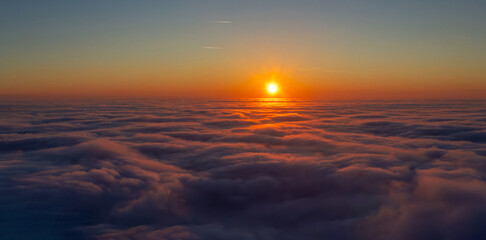 A vibrant sunrise viewed from above the clouds. Aerial view of a sunrise above the cloud layer