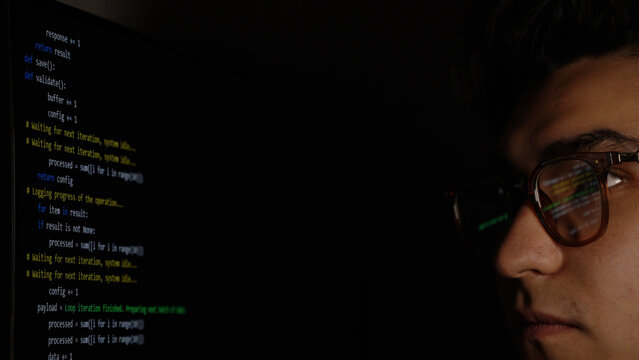 Focused man looking at trading charts on multiple screens in dark room. - Powered by Adobe