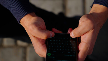 Close up of man's hands typing on smartphone screen while traveling.