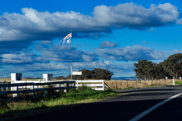 tattered Australian flag flying by entrance to farm property