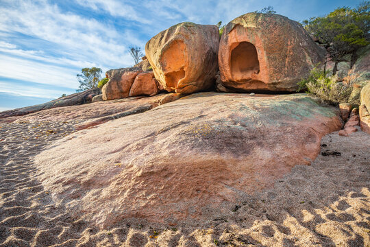 Large weathered rock formations covered in lichen, perched on a granite ledge