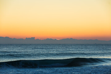 Sunrise Light Obscured by Low Clouds Along Rolling Coastal Waves