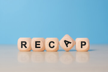 recap sign made of blocks on a table with a reflective surface, blue background