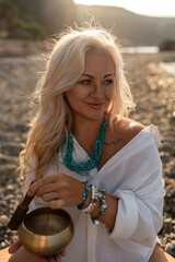 Woman meditation beach singing bowl during golden hour sunset for spiritual wellness