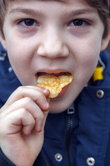 Boy is eating a snack while wearing a blue jacket