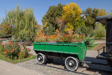 A children's train with a trailer styled as a flower bed in a city park.