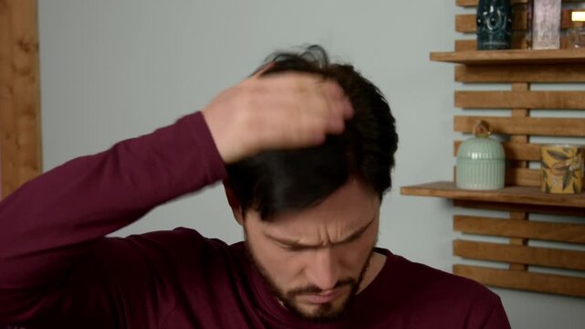 Shocked attractive bearded middle aged man looking at mirror, finding out dandruff problems, cleaning head from heavy flaking and itchiness, expressing irritation and worries in bathroom.