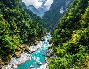 Turquoise river flows through a lush, green valley with misty mountains in the distance under an overcast sky
