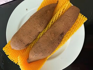 Two raw sweet potatoes resting on vibrant yellow mesh packaging on a clean white plate