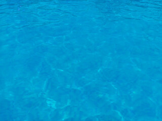 Fototapeta premium Clear blue swimming pool water surface with gentle ripples and light reflections. Fresh aquatic texture background with copy space, summer relaxation and clean water concept