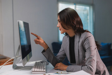 Professional woman pointing at computer screen in office