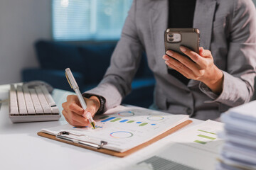 Businesswoman analyzing corporate data while using smartphone