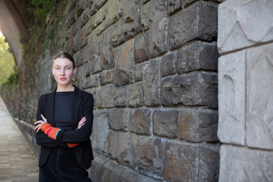 Self-confident urban teenage girl standing by stone wall in Aachen