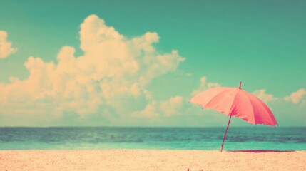 Fototapeta premium Pink umbrella stands on sandy beach under blue sky with clouds