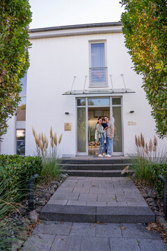 Family standing together at home entrance showing pride and unity