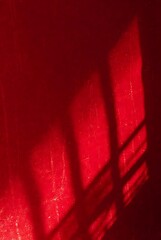 Abstract red background with diagonal shadows creating a geometric pattern, conveying a sense of mystery and intensity