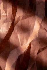 Textured crumpled paper with warm, diffused lighting creating abstract patterns and shadows, conveying a sense of warmth and depth